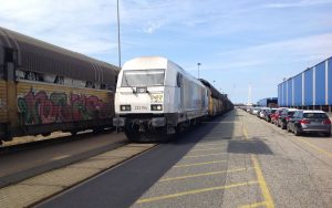 Baureihe 223 in Bremen Rangierbahnhof ankommend, fabrikneue Autos warten auf Transport auf der Schiene