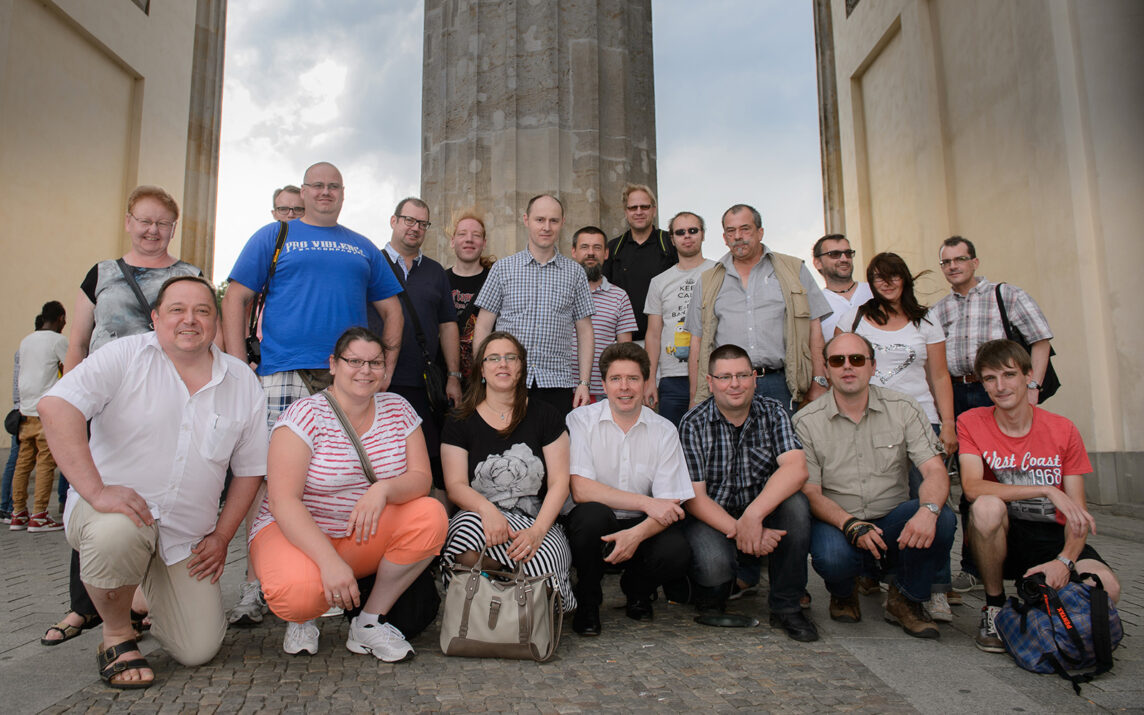 Railmen Mitarbeiter posieren zusammen für ein Gruppenbild unterm Brandenburger Tor.