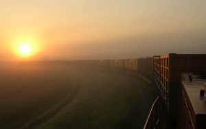 Ein langer Güterzug bahnt sich den Weg durch die reizvolle Morgenstimmung über der Ebene bei Neuburg an der Donau