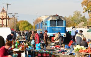 Markttrubel auf den Gleisen von Vinogradov in der Ukraine während sich die blaue Schmalspurbahn nähert.