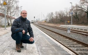 Railmen-Lokführer Jan Krehl posiert hockend am Bhf Grimma.