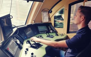 Triebfahrzeugführer sitzt im Führerstand und bedient die Steuerhebel