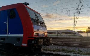 ICE mit grüner Bauchbinde überholt Güterzug bei Augsburg