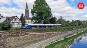 Nordwestbahn (NWB) in Höxter. Im Vordergrund ist die Weser zu sehen und der Zug befindet sich auf dem Weg von Holzminden nach Paderborn.